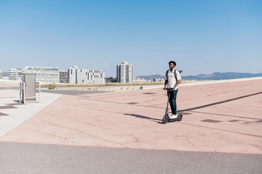 Stylish man riding electric scooter in city