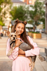 Teen girl with pet animal small dog holding in a hands outdoor in a park