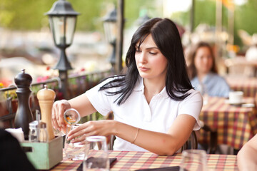 Beautiful young brunette woman sitting at cafe with her friends. Communication and friendship concept
