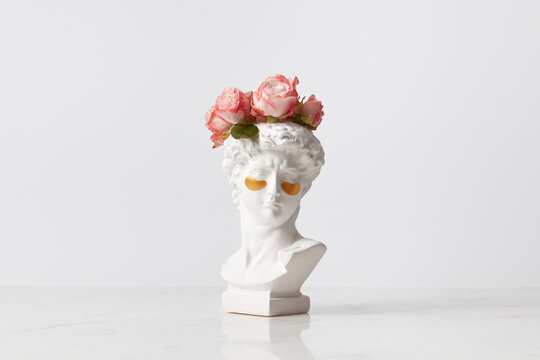 Statue of goddess head with eye patches and flowers