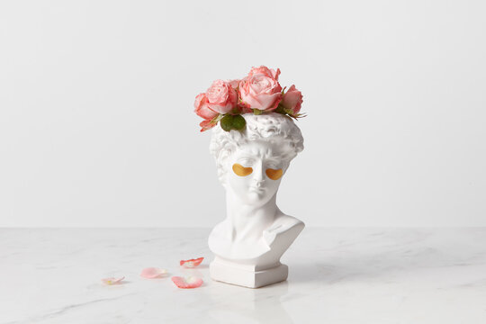 Bust of goddess head with eye patches and flowers