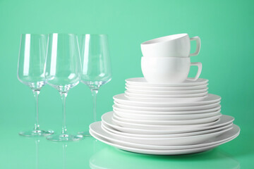 Set of clean tableware on light green background