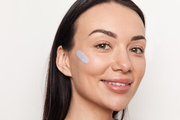 Young smiling woman with blue concealer on her face