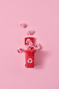 Crumpled papers in trash can on pink background