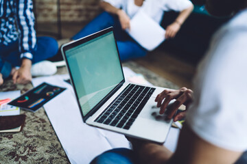 Cropped image of male IT professional using laptop application for browsing website and research publication, selective focus on modern netbook computer used during collaborative meeting in coworking