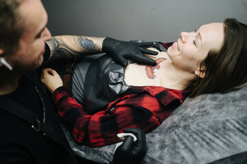 Smiling woman with red bird tattoo preparing for session in tattoo studio