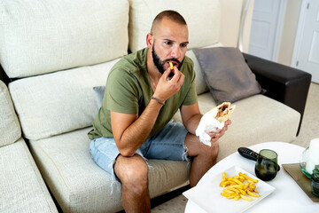 Man eating a sandwich with potatoes at home