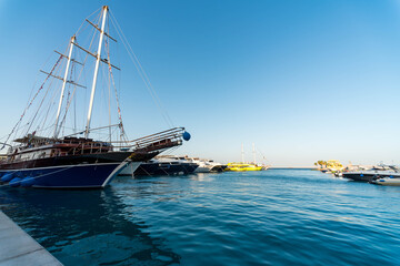 empty pier without people with a sailboat with modern ships and boats
