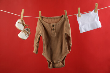 Baby clothes hanging on washing line against red background
