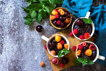 Summer breakfast or dessert. Chocolate cupcake in a mug is served with fresh summer berry raspberries and cherries. Top view flat lay background. Copy space.