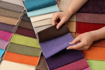 Woman choosing fabric among multicolored samples, closeup