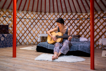 Woman Playing Guitar In A Yurt. 
