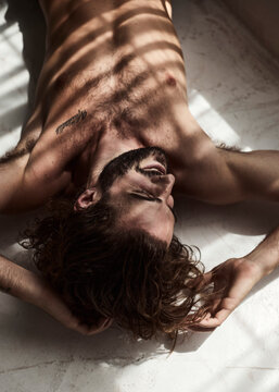A sexy shirtless man lying on the floor in a grungy setting