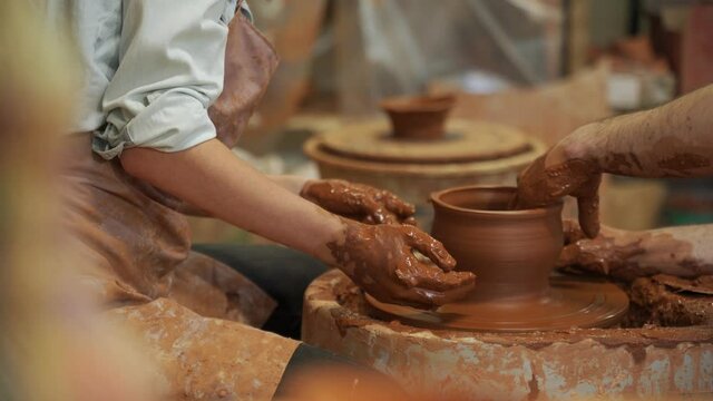 Pottery classes, woman making clay pot on wheel. Close-up of dirty hands, sculpting clay crockery masterclass pottery training