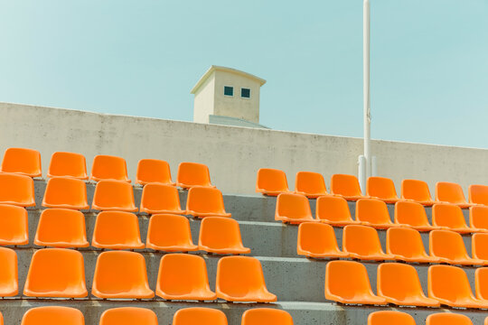 The orange color bleachers are empty inside the stadium