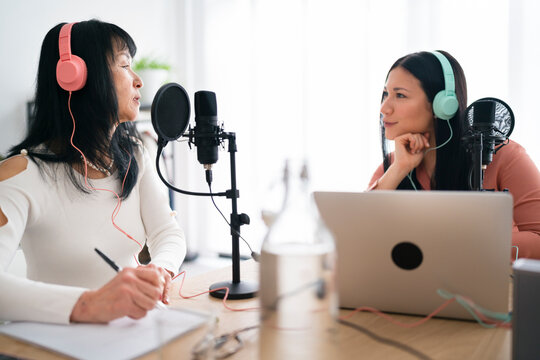 Podcasters in headphones recording audio program together