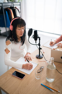 Woman taking notes and recording podcast
