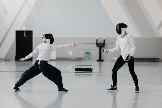 Fencers with swords training in gym