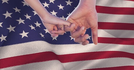 Naklejka premium Composition of two hands linking little fingers, making pinkie promise, over billowing american flag