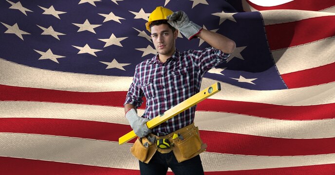 Composition of smiling male construction worker over billowing american flag