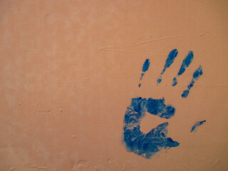 Brown wall with a print of the left palm of a person. Wall texture with white spots. Bottom right corner. 