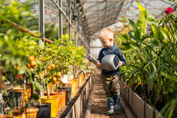 Boy in a greenhouse with a watering can in his hands