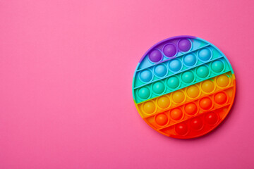 Simple dimple or pop it game on pink background with place for text. Top view of Push Pop Fidget Toy on color background. Silicon sensory anti stress toy