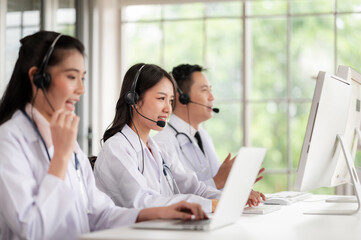 Asia medical service team health advice online. Smiling face stood wearing the headphones with a microphone and stethoscope in clinics.Concept of remote medicine, health care call center online.