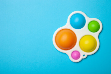 Simple dimple or pop it game on blue background with place for text. Top view of Push Pop Fidget Toy on color background. Silicon sensory anti stress toy