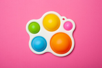 Simple dimple or pop it game on pink background. Top view of Push Pop Fidget Toy on color background. Silicon sensory anti stress toy