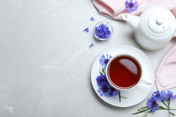 Composition with tea and cornflowers on light table, flat lay. Space for text - obrazy, fototapety, plakaty