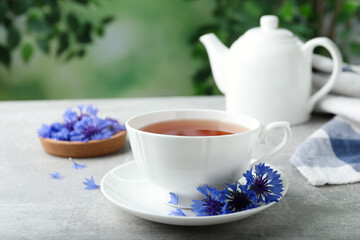 Cup of tea and cornflowers on light table - obrazy, fototapety, plakaty