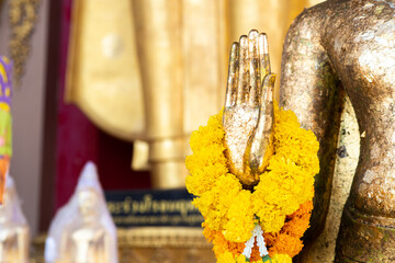 Buddha statue with raw of Brass. Hand of buddha statue with. marigold garland and rose garland. Believe, Culture, Traditional. Buddhist believe and merit. Calm and meditation concept.