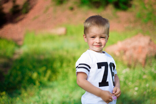 Little boy of two years old posing and looking at the camera on nature in summer.