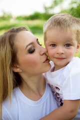 Young mom kisses her son and walking in the park