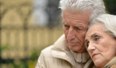 Sad thoughtful senior couple in  park