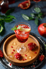 Pomegranate refreshing summer cocktail on dark background. Summer cocktail
