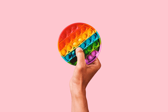 man pops a bubble of a rainbow toy