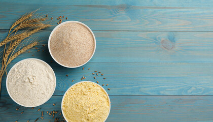 Different types of flours and wheat ears on light blue wooden table, flat lay. Space for text