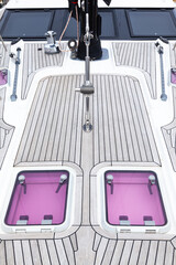 Deck of a sailing yacht in teak wood with hatches and deck yacht equipment, top view.