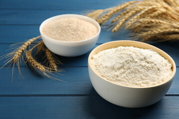 Bowls of flours and wheat ears on blue wooden table