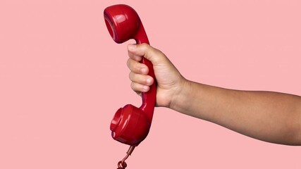 Hand holding the receiver of a retro red telephone