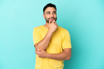 Young arab man isolated on blue background thinking an idea while looking up