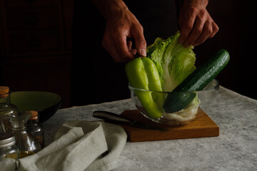 Fresh green vegetables in a glass cup. A man is going to prepare a veggie salad of green...