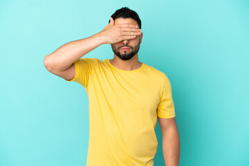 Young arab man isolated on blue background covering eyes by hands. Do not want to see something