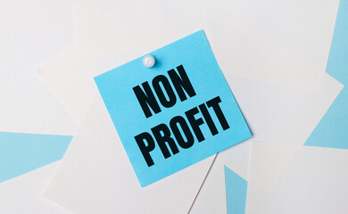 On a light blue background, white square sheets of paper. A light blue square sticker with the text NON PROFIT is attached to them using a white paper clip.