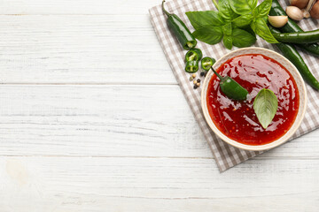 Spicy chili sauce and ingredients on white wooden table, top view. Space for text