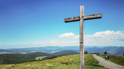 Wonderful view from Belchen hill mountain, surrounded by green fresh meadow, forest trees, wooden cross and people who hike  - Landscape Southern Black Forest Aitern Germany background panorama