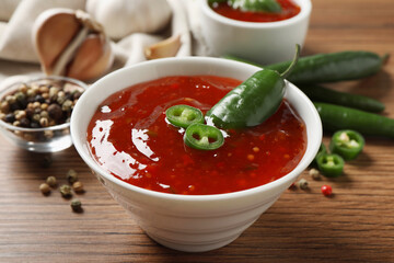 Spicy chili sauce in bowl on wooden table