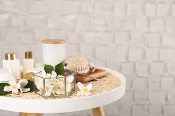 Composition with beautiful jasmine flowers and skin care products on white table, space for text